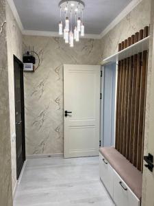 um corredor com uma porta branca e um lustre em Miracle Apartment em Samarkand