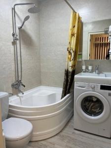 bagno con vasca, servizi igienici e lavatrice. di Miracle Apartment a Samarkand