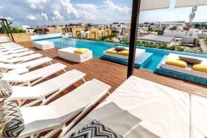 a balcony with white lounge chairs and a swimming pool at Estudio exclusivo in The City - TOP amenidades! in Playa del Carmen