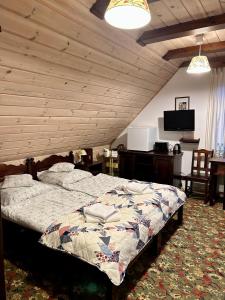 sypialnia z łóżkiem i drewnianym sufitem w obiekcie Leśne PoBudki w Białowieży