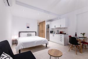 a white bedroom with a bed and a kitchen at Pagani Blue - Luxury Studio A2 in Faraí