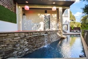 a house with a swimming pool and a stone wall at Villa Alana in Los Angeles