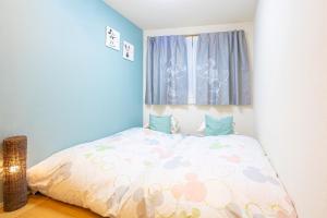 ein kleines Schlafzimmer mit einem Bett mit einer Bettdecke in der Unterkunft CuteFamilyHouse! 3LDK 6minShinjuku 3minJRsta Cozy,Fun,Bright! KidsFree Under6yrs in Tokio