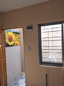 Zimmer mit einem Fenster und einem Gemälde einer Sonnenblume in der Unterkunft Los Girasoles del Sur in Wilde