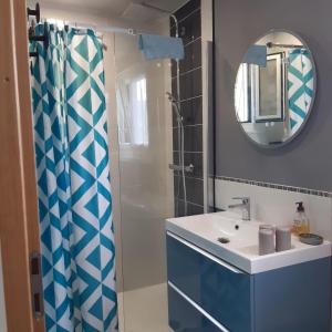 uma casa de banho com uma cortina de chuveiro azul e um lavatório. em PILOUBELLE 