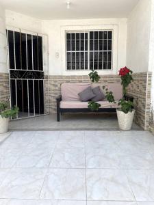 a couch sitting on a porch with two potted plants at Casa Carolina in Santa Marta