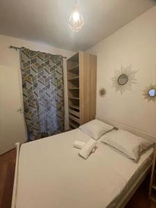 a small bedroom with a white bed and a mirror at Le floquet in Vitry-sur-Seine