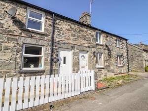 an old stone house with a white fence at 2 White Street in Penmachno