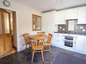 a kitchen with a wooden table and four chairs at 2 White Street in Penmachno