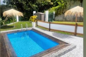 a swimming pool in a yard with two umbrellas at Palmier bungalow- piscine in Gros-Morne