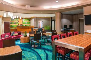 a hotel lobby with red chairs and tables at SpringHill Suites Fort Myers Airport in Fort Myers