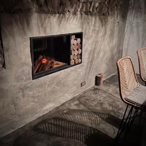a fireplace in a stone wall with two chairs at Twilight Forest in Jiufen