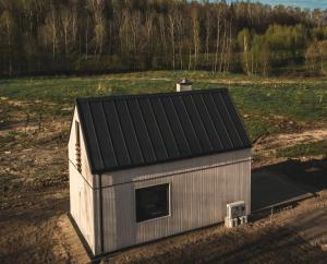 a small shed with a black roof in a field at Las Angels in Morąg