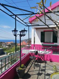 un balcon rose avec une table et une lumière de rue dans l'établissement Westerland House, à Ribeira Brava