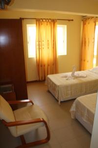 Habitación con 2 camas y una silla. en Hotel Lazareto en Mindelo