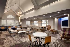 a lobby with tables and chairs and a tv at Residence Inn by Marriott West Springfield in West Springfield