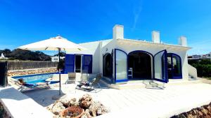 a blue and white house with a pool and an umbrella at Binibeca Vell Luxury Villa, sea direct access, private pool in Binibeca