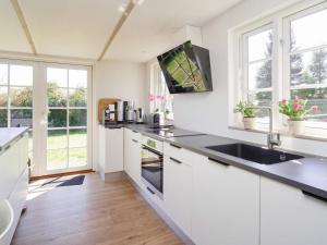 a kitchen with white cabinets and a sink and windows at 6 person holiday home in Kalundborg-By Traum in Kalundborg +15 photos