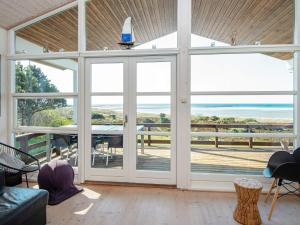 d'un salon avec des portes coulissantes en verre et une vue sur l'océan. dans l'établissement 6 person holiday home in Ebeltoft, à Ebeltoft