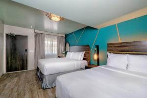 two beds in a hotel room with blue walls at Marea Sol Hotel in Santa Cruz