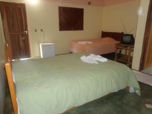 a hotel room with two beds and a television at Pousada Chalés do Lago in Cavalcante