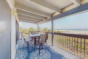 een balkon met een tafel en stoelen en het strand bij Gulf's Hidden Treasure in St Pete Beach