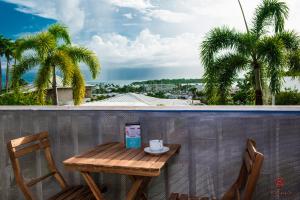 a wooden table and chairs on a balcony with palm trees at Appartement moderne à la Marina du Gosier in Le Gosier