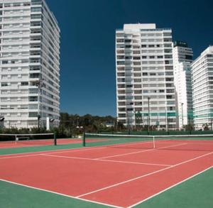 un court de tennis avec de grands bâtiments en arrière-plan dans l'établissement Apartamento frente ao mar Punta del Este, à Punta del Este