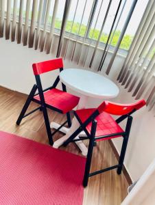 リオデジャネイロにあるStudio perto de tudo vista Mar Flamengoの白いテーブルと窓際の赤い椅子2脚
