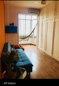 uma sala de estar com um sofá azul e uma grande janela em Studio perto de tudo vista Mar Flamengo no Rio de Janeiro