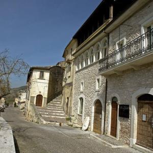 an old stone building with stairs next to a street at La Loggia Di Federico in Navelli