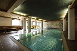 a swimming pool in a building with a tile floor at Hotel Am Fels in Senales