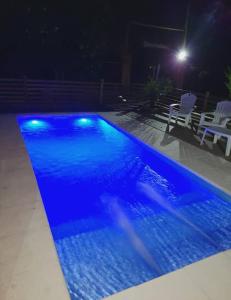 una piscina azul por la noche con 2 sillas en Casa de Campo, con Pileta y Asador Criollo!! - "La Ranchada" en Gualeguaychú