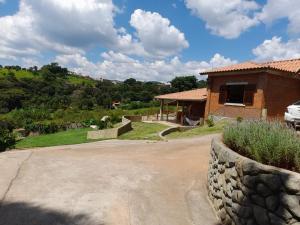 ein Haus mit einer Steinmauer neben einer Auffahrt in der Unterkunft Chácara Picapau Amarelo in Socorro