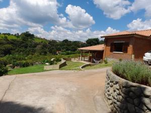 a house with a stone wall next to a driveway at Chácara do Picapau Amarelo in Socorro