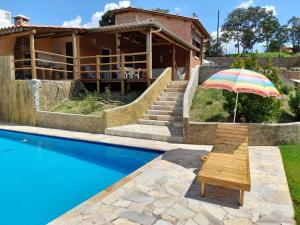 a chair with an umbrella next to a swimming pool at Chácara do Picapau Amarelo in Socorro