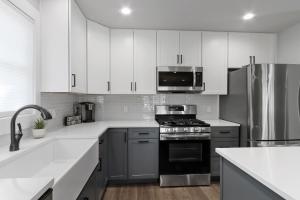 una cocina con electrodomésticos de acero inoxidable y armarios blancos en Williams Bay House - Cherry Street Retreat en Lake Geneva