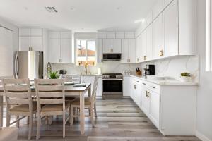 cocina con armarios blancos, mesa y sillas en Adorable 3 bedroom with Jacuzzi & more en Los Ángeles
