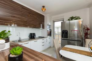 cocina con armarios blancos y nevera de acero inoxidable en Apartments with a parking space Kastel Gomilica, Kastela - 21138, en Kaštela