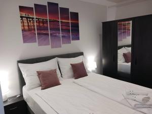 a bedroom with a large white bed with paintings on the wall at Apartments by the sea nska, Krk - 21205 in Malinska