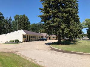 a car parked in front of a building with a tree at Yellow Quill Motel in Portage La Prairie