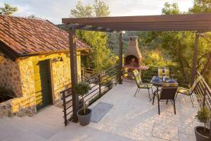 eine Terrasse mit einem Pizzaofen, einem Tisch und Stühlen in der Unterkunft Secluded house with WiFi Zlarin - 21177 in Zlarin