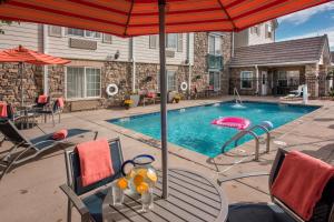 a swimming pool with a table and an umbrella at Suburban Studios Denver Tech Center in Denver