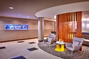 a lobby with two chairs and a table and a tv at SpringHill Suites Lehi at Thanksgiving Point in Lehi