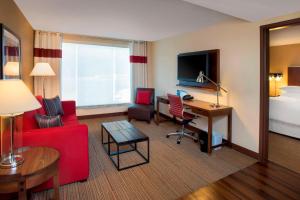 une chambre d'hôtel avec un canapé rouge et un bureau dans l'établissement Four Points by Sheraton Charleston, à Charleston
