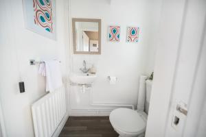 a white bathroom with a toilet and a sink at Spacious 3 bed house w/ garden, parking, WiFi, TV in Coventry