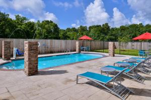 a pool with chairs and umbrellas next to a fence at TownePlace Suites by Marriott Laplace in Laplace