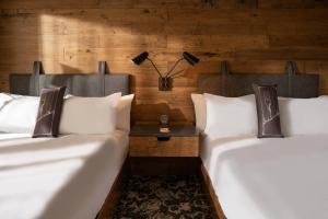 2 łóżka z białymi poduszkami w pokoju z drewnianymi ścianami w obiekcie Epicurean Atlanta, Autograph Collection w Atlancie