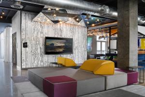 a lobby with yellow and purple chairs and a wall at Aloft Austin Round Rock in Round Rock