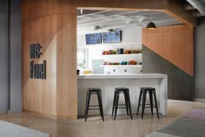 a kitchen with a bar with stools and a window at Aloft Austin Round Rock in Round Rock